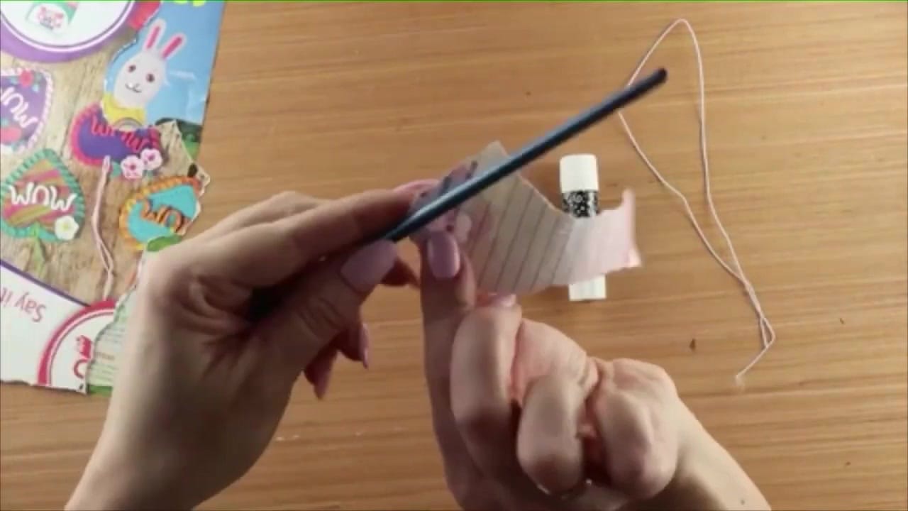 A strip of paper being rolled tightly around a skewer to form a bead.