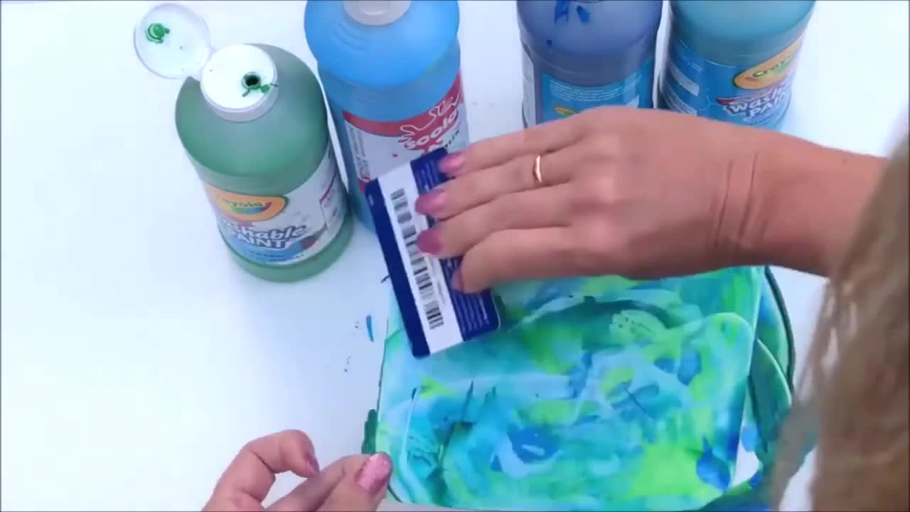 Blobs of colourful paint scattered on thick card ready for scraping.