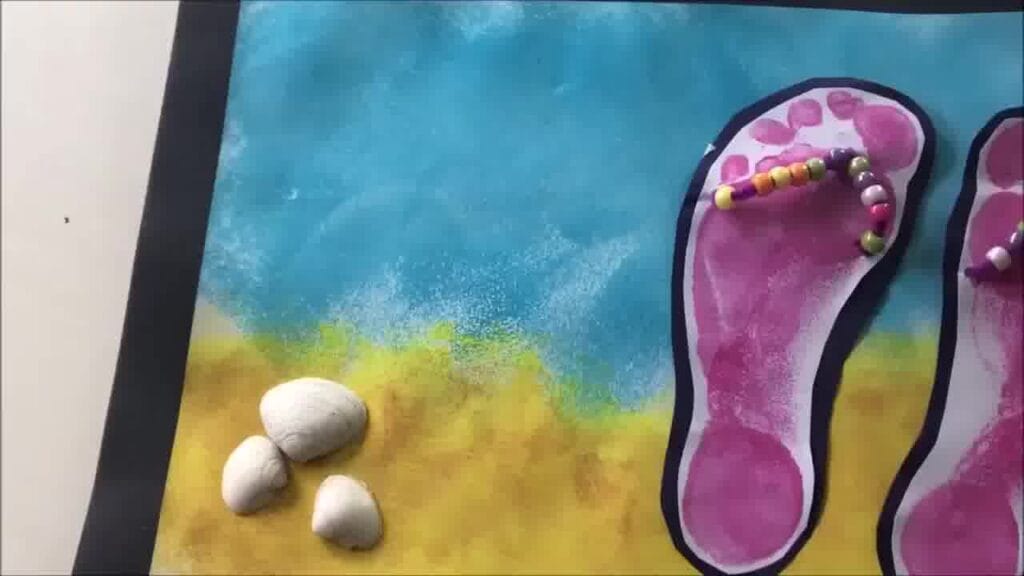 Finished beaded flip flops craft – vibrant footprint flip flops decorated with beads and displayed on a seaside-themed background.