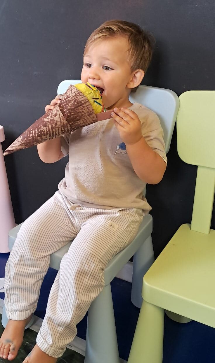 Child holding up their completed ice cream craft with a big smile