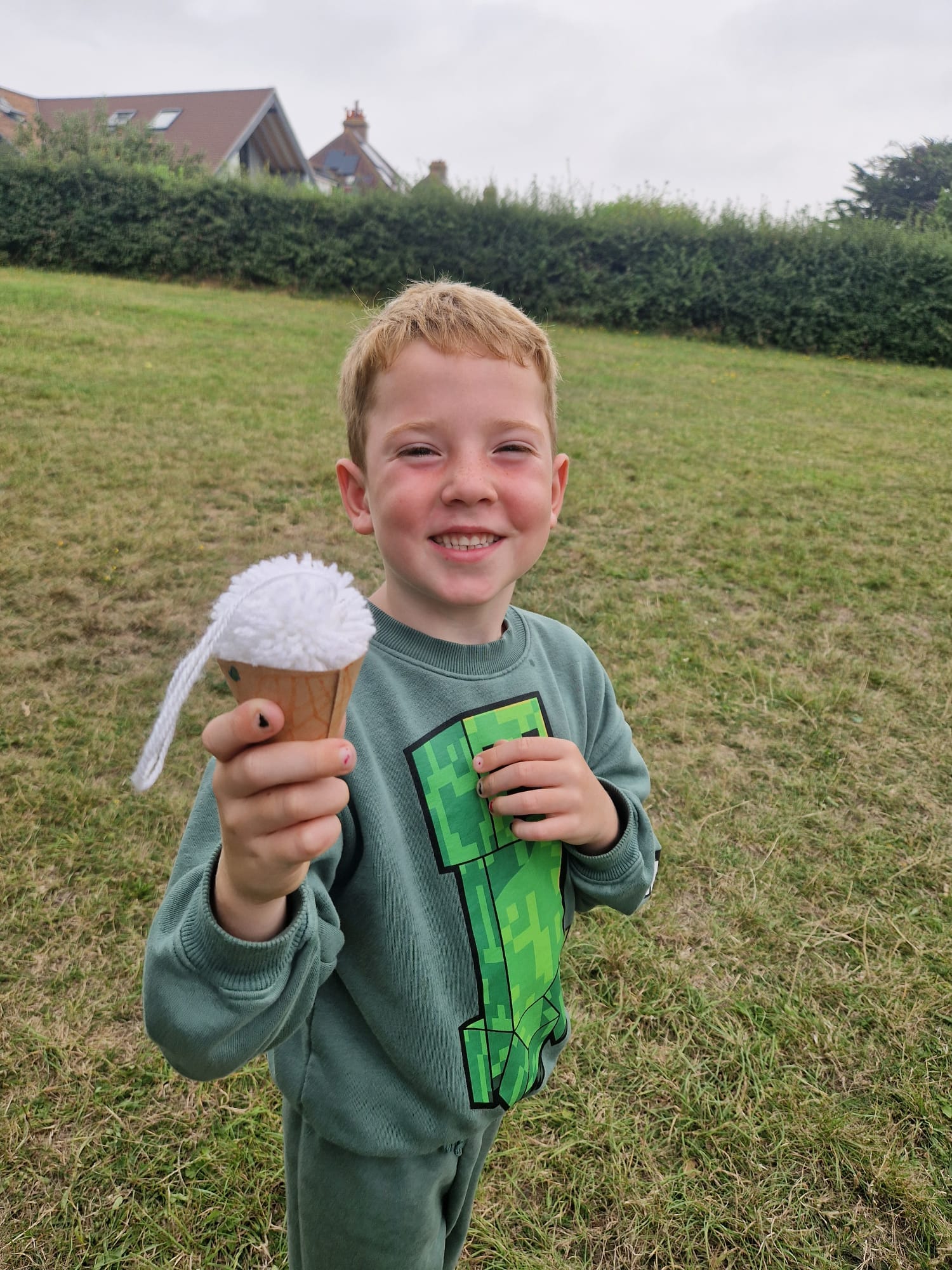 Child holding up their completed ice cream craft with a big smile.