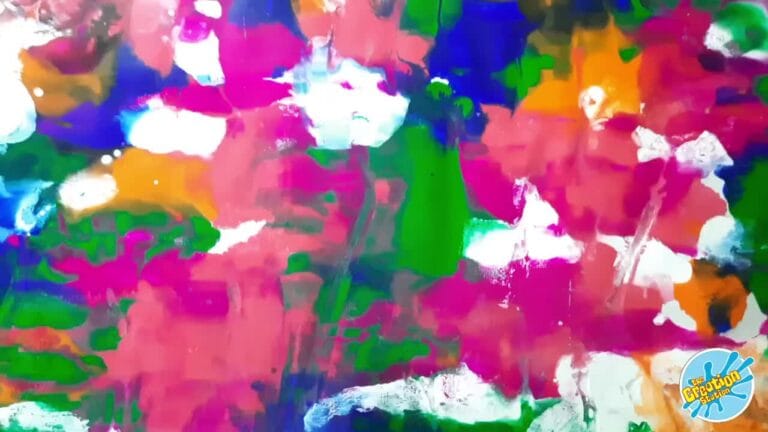 Close-up of colorful paint being poured onto the canvas to create fluid patterns.