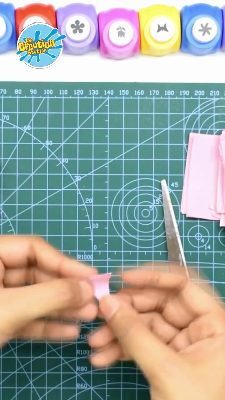 Hands gluing petals together around a central point to form the paper flower