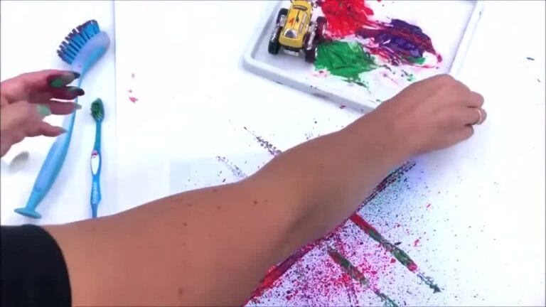 Hands experimenting with different tools like squeegees and brushes to make fun paint effects