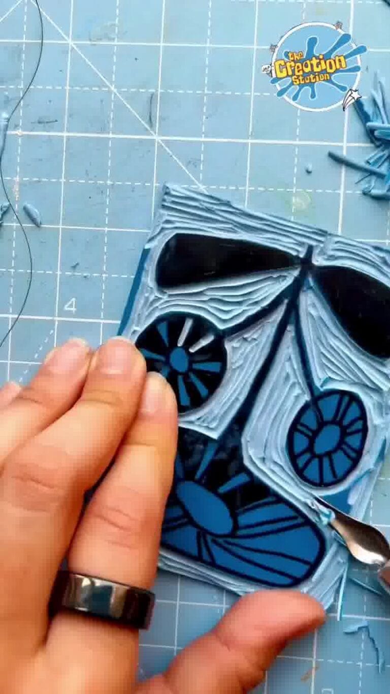 Hands carefully carving along the pencil lines to create the raised printing surface