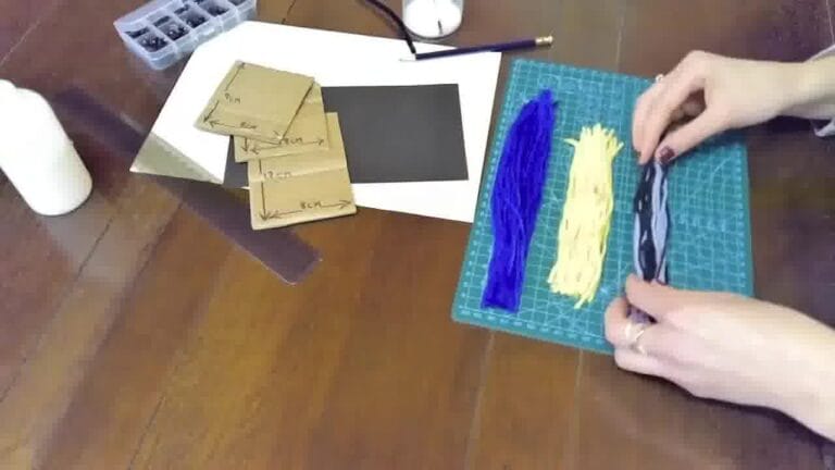 Hands wrapping yarn tightly around a small cardboard or wire frame to form the base of the bird’s body